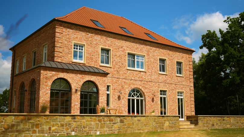 Helles, zweistöckiges Ziegelhaus mit Rotklinker und großen Fenstern.