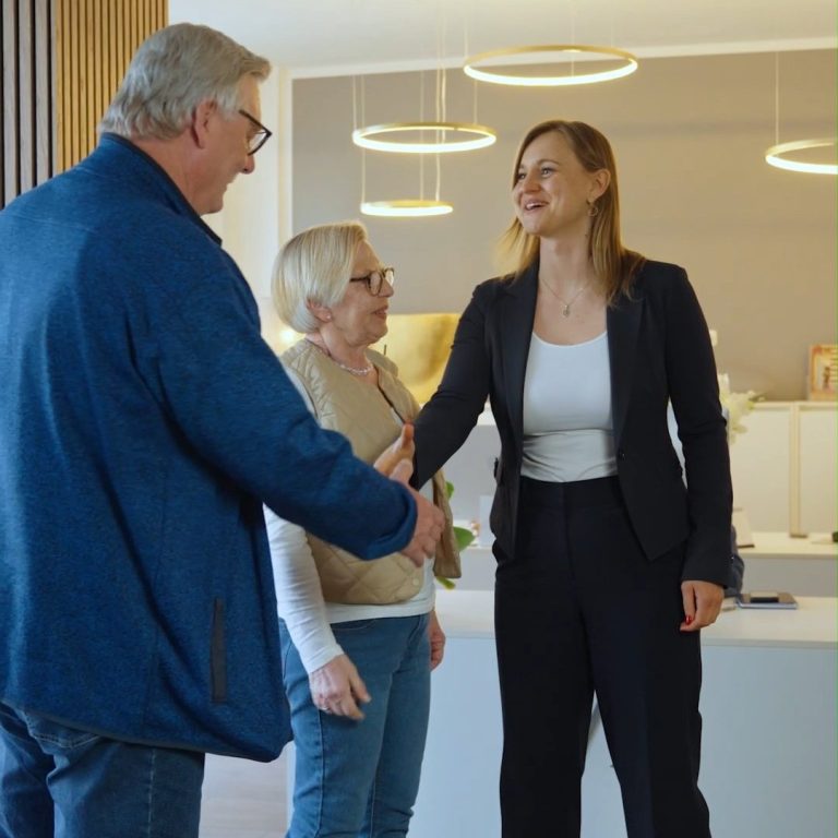 Ein Mann und eine Frau schütteln der Geschäftsfrau die Hand in einem modernen Büro.