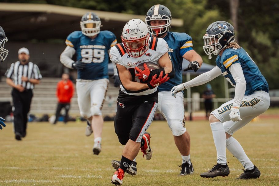 Ein Footballspieler umdribbelt Gegner auf dem Spielfeld.