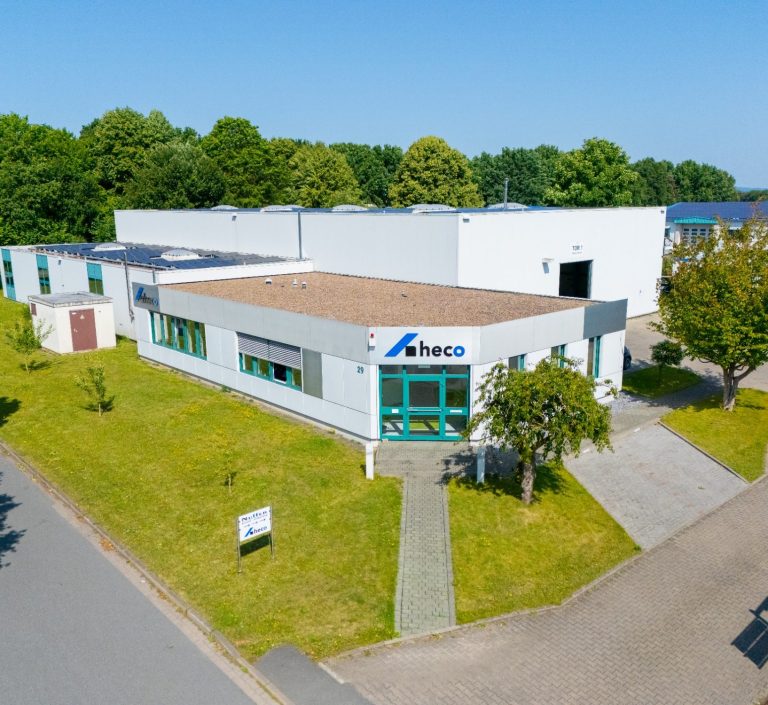 Moderne Gewerbeimmobilie mit begrüntem Außenbereich und klarem blauen Himmel.