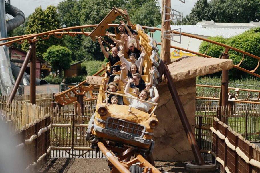 Fahrgeschäft mit einer Gruppe von Personen, die auf einer Achterbahn im Freien Spaß haben.