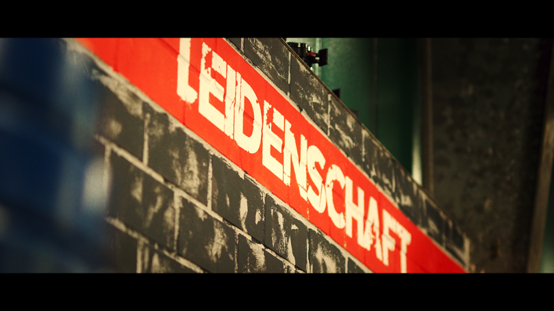 Roter Schriftzug „LEIDENSCHAFT“ auf einer strukturierten Wand.